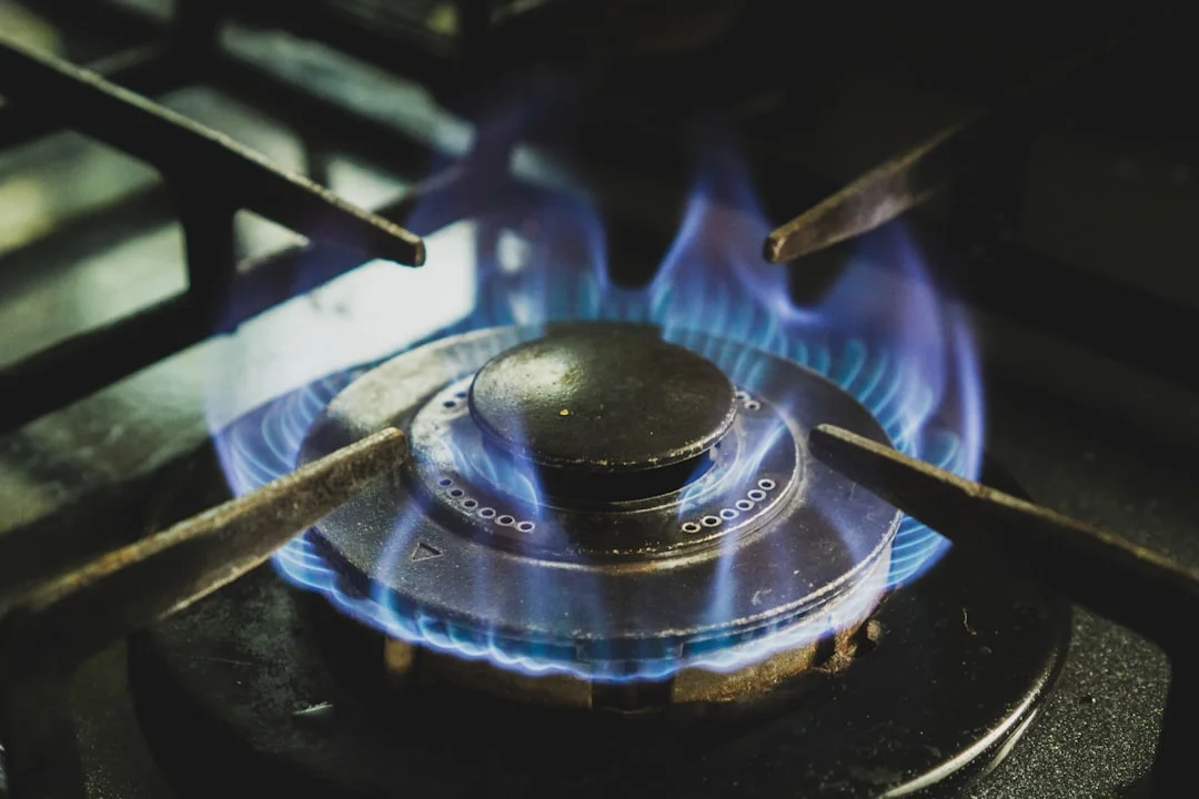 A 36-inch professional BlueStar propane range with brass burners glowing blue in a warm, renovated farmhouse kitchen, cast iron grates centered in frame